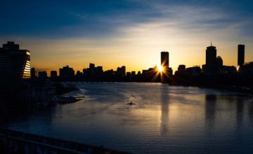 Sunrise over the Charles River with rower on river in front of the Boston skyline