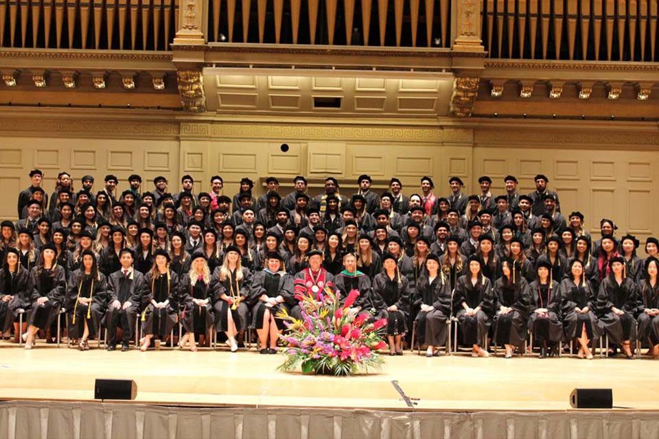 students sitting and standing in graduation robes