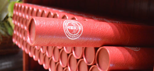 Stack of diploma in cardboard tubes with NECO academic seal imprinted.
