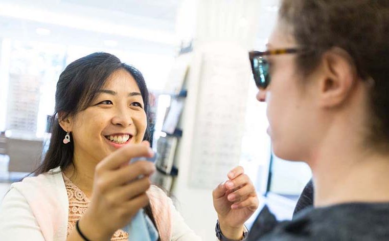 Student helps patient pick glasses frame