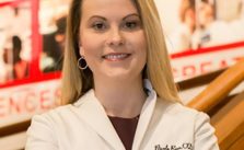 Dr Nicole Ross in a lab coat with her arms crossed confidently.