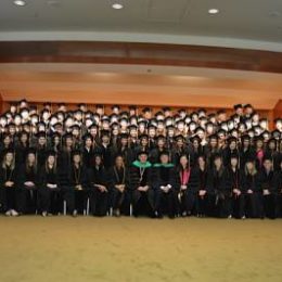 group of students sitting and standing in caps and gowns