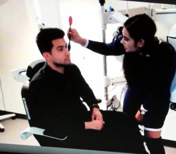 female student practicing eye exam on male