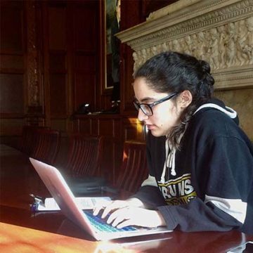 female student with glasses sitting and using laptop