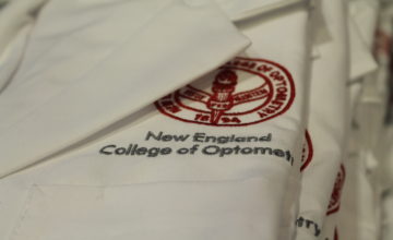 NECO seal embroidered on folded white lab coat.