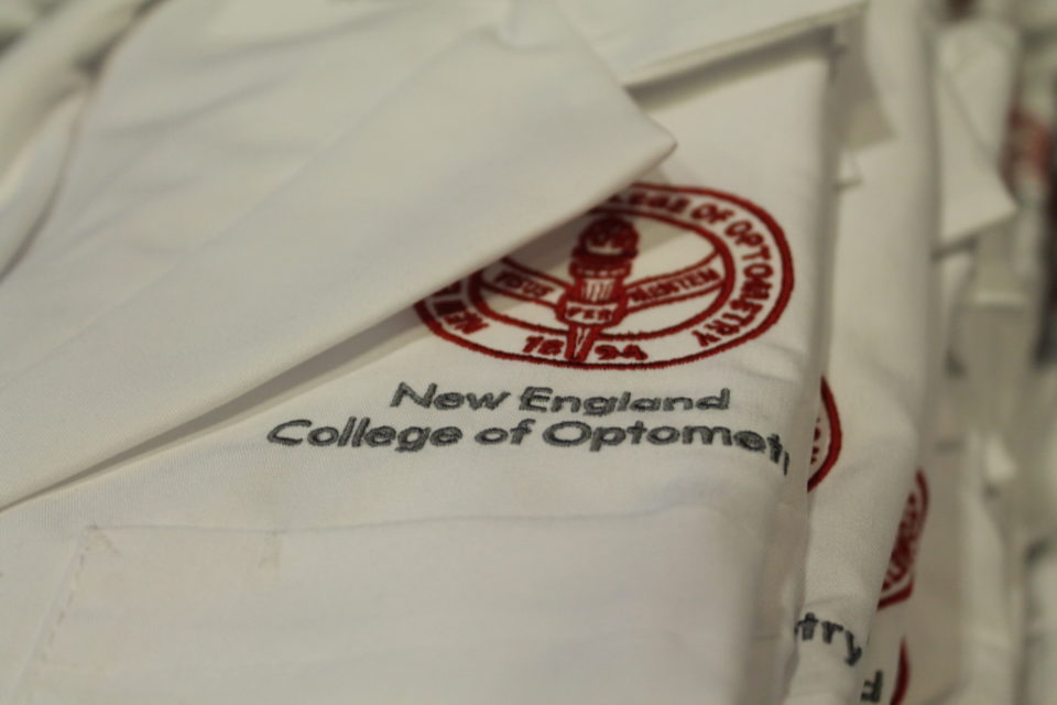 NECO seal embroidered on folded white lab coat.