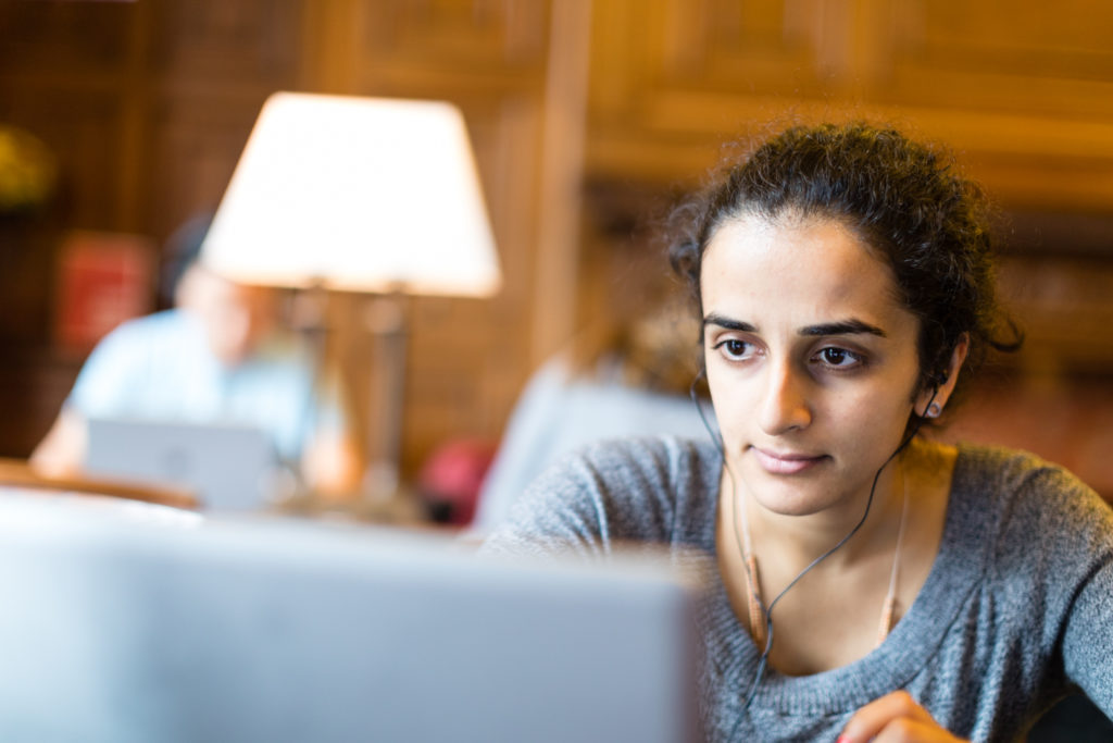 Female student looking at laptop in library