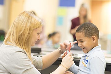 Student giving vision screening to young student in Boston schools
