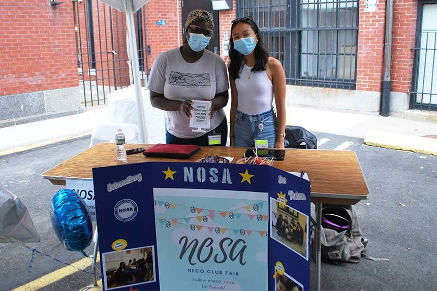 two students posing by table with trifold board in front