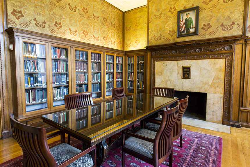 Cozy room with wood, glass bookcases, conference table and fireplace.