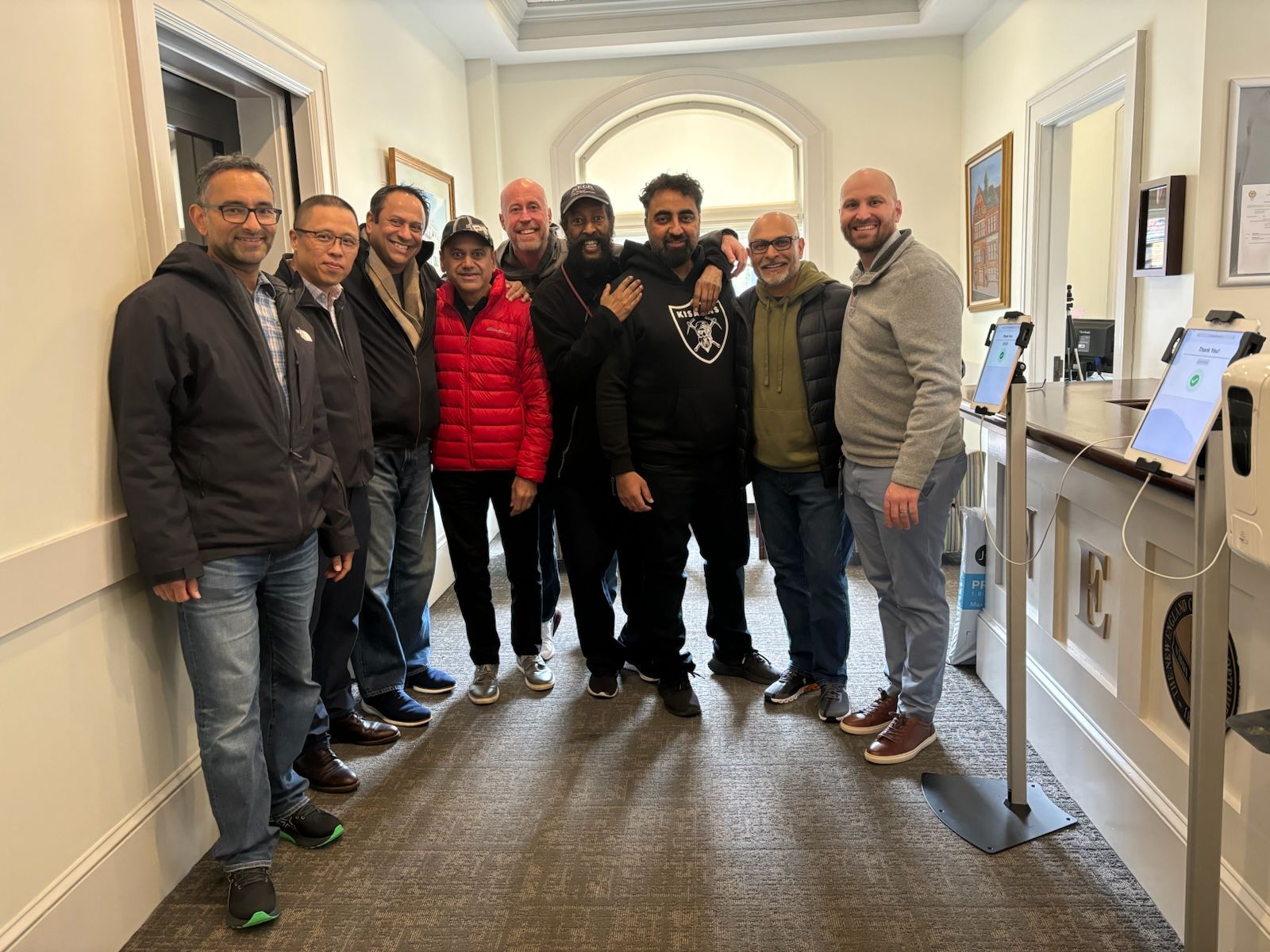 group of nine men standing next to front desk office