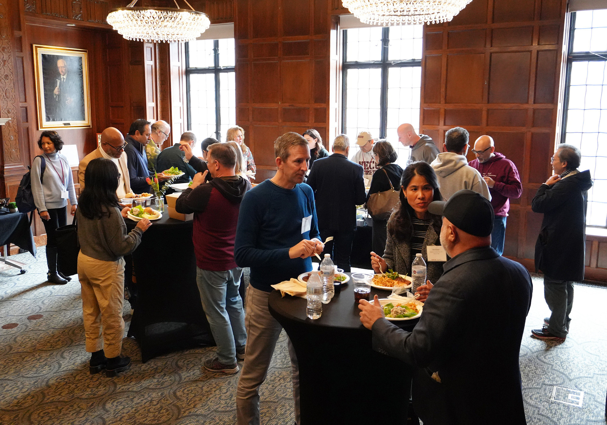 crowd of people standing and eating at high top tables 
